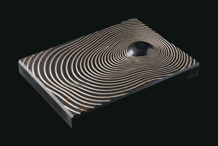 Etched topographic lines converging across dark mineral.